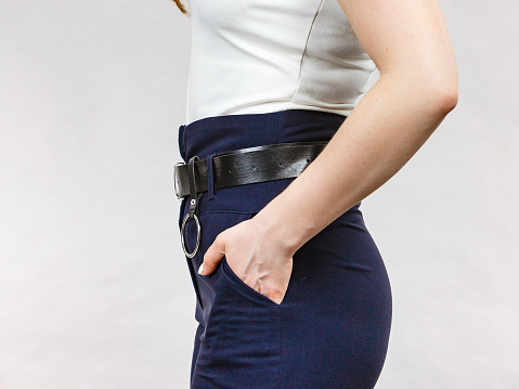 Business woman wearing suit, blue high waist pants with black leather trouser belt. Clothing detail.