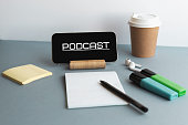 smartphone with the inscription podcast, wireless headphones, notepad, markers, coffee cup, online education concept 1