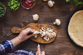 Woman cutting mushrooms for pizza at home