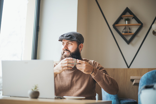 a young man with a beard takes a break and drinks coffee in a cafe