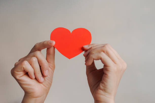 istock women's hands holding red heart shaped postcard, surprise gift for Valentine's day. 1955815847