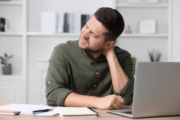 istock Man suffering from neck pain in office 1955824446