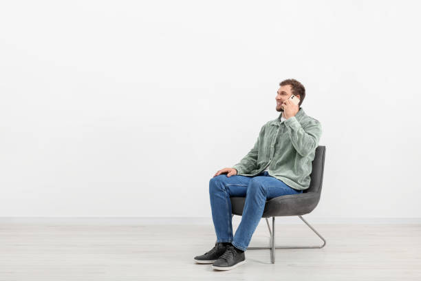 istock Young man talking on smartphone while sitting on chair indoors. Space for text 1955824977