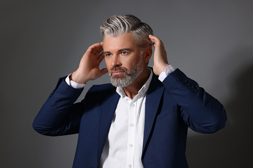 Portrait of confident man with beautiful hairstyle on dark grey background