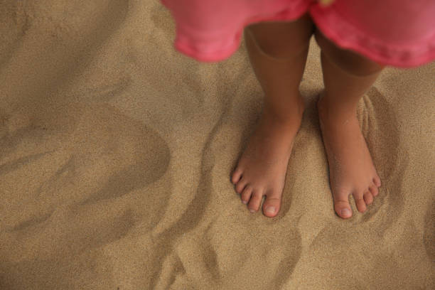 istock Little girl standing on sandy beach, closeup. Space for text 1955840923