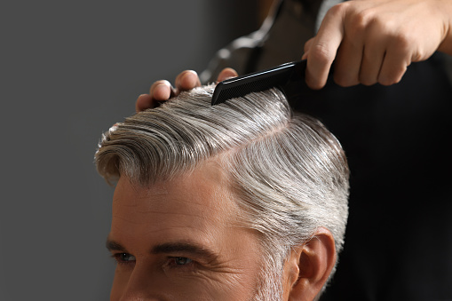 Hair styling. Professional hairdresser working with client in barbershop, closeup
