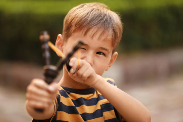 istock Little boy playing with slingshot in park 1955845637
