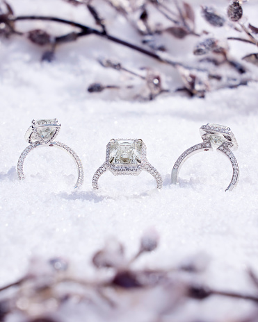 Three engagement rings placed in the snow create a picturesque scene, capturing the essence of love and the tranquility of winter.