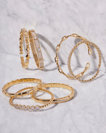 A collection of three gold bracelets and a ring elegantly displayed on a smooth marble surface.