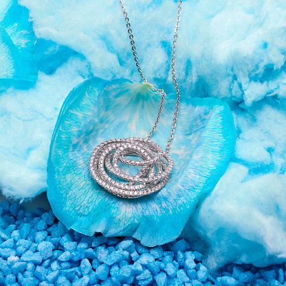 This photo shows a necklace adorned with a beautiful blue flower embellished with a spiral design.