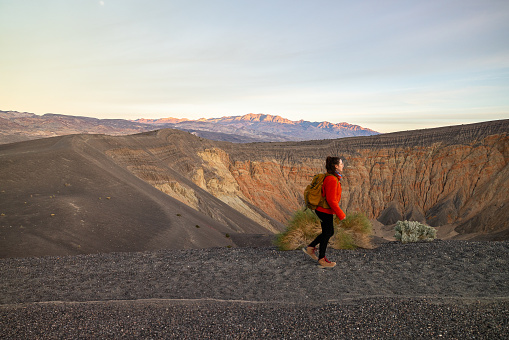 Captured on the rim of Ubehebe Crater in Death Valley National Park, young woman walking along the edge of this ancient volcanic field