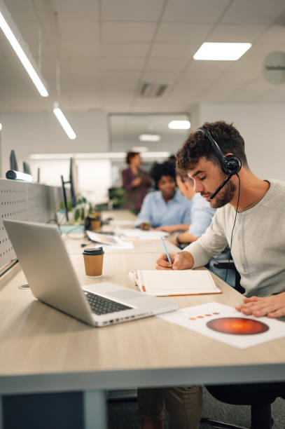 istock Businessman working in a call center on the line and using headset and a laptop 1955876595