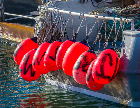 Bright red industrial fishing buoys hang from the stern of a fishing boat docked at the Sandwich Marina on the Cape Cod Canal.