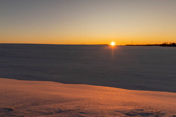 winter field covered with snow at sunset, beautiful multicolored sky at sunset in winter