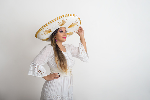 Mexican woman wearing a mariachi hat. Woman with sombrero, white background.