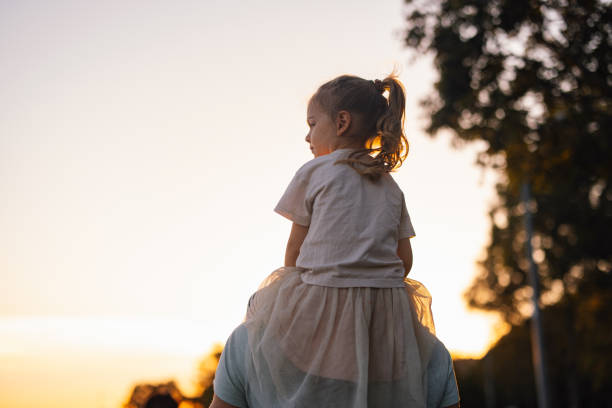 a happy cute little girl looking away while sitting on  her father's shoulders - pensive only baby girls baby girls baby foto e immagini stock