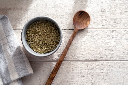 Dried thyme in bowl on white wooden background