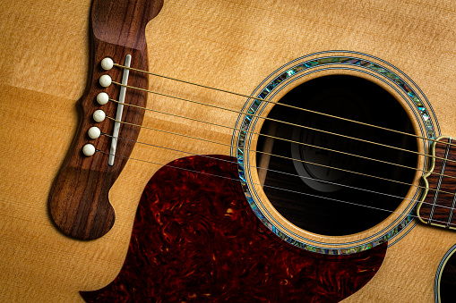 A vintage microphone in a professional recording studio. A guitar is on the backgraound.