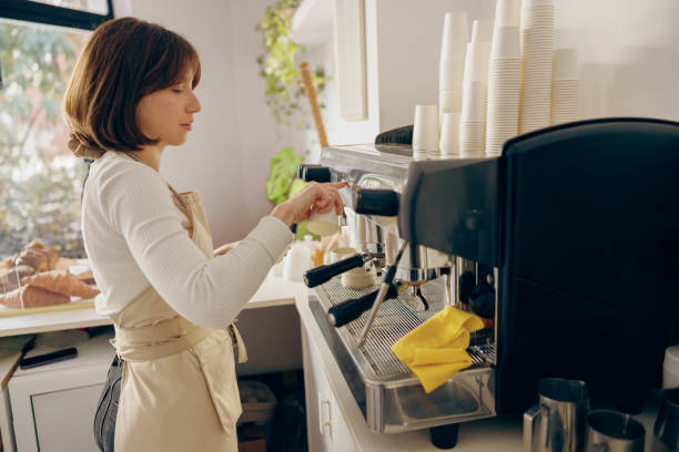 istock Professional female barista making coffee in a coffee machine while working in cafe 1955928985