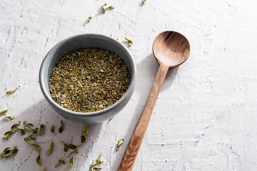 Dried thyme in bowl on white textured stone background