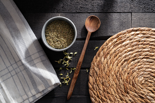 Dried thyme in bowl on black wooden background