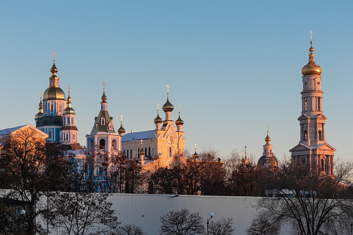 City landscape with Christian churches. Blue clear sky above golden domes with crosses. Kharkiv city, Ukraine