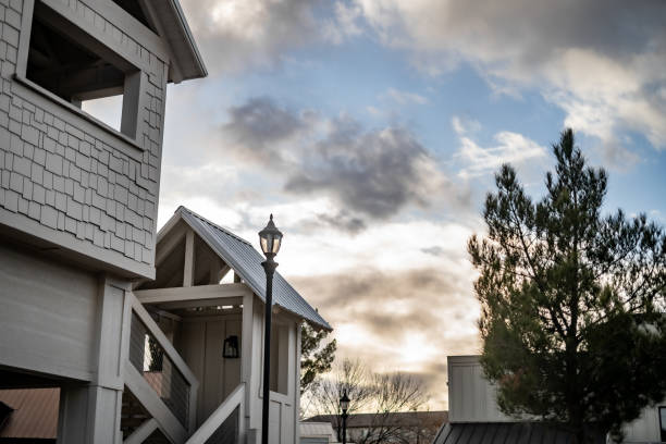 istock Rooftops Small Buildings With Lamp Light Partially Cloudy Blue Sky Treetops 1956062814