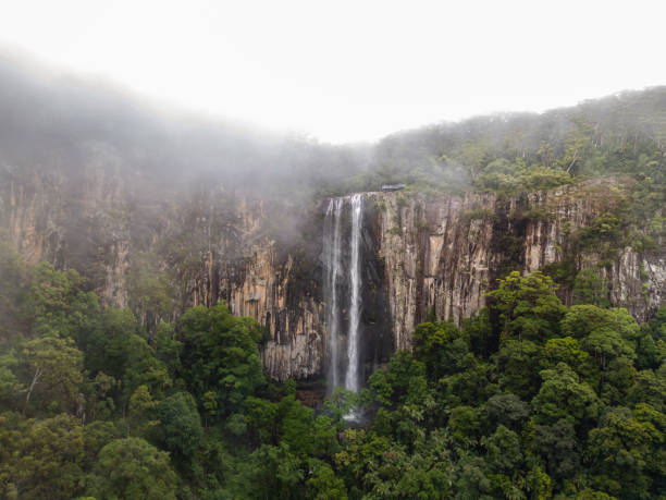 istock Slow moving clouds swirling around the cliff face at Minyon Falls, Australia 1956077643