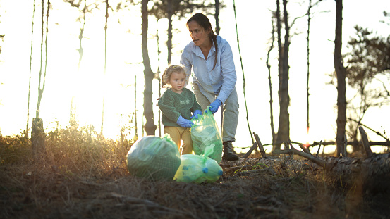 Activist mom and kid cleaning nature. Teaching children about sustainability and recycling concept.