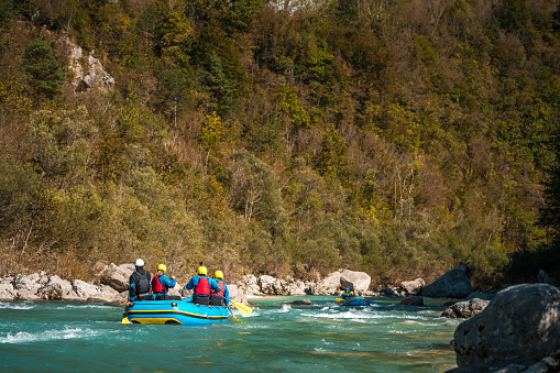 Enthusiastic rafters wearing safety helmets and life vests engage the rapids, enjoying the challenges of the swift water currents.