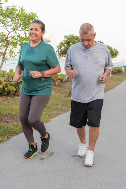 istock older woman jogs beside focused man 1956122928