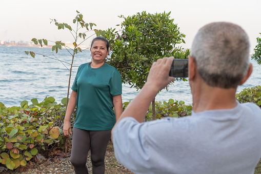 Senior woman posing for a photo by a male photographer with sea background