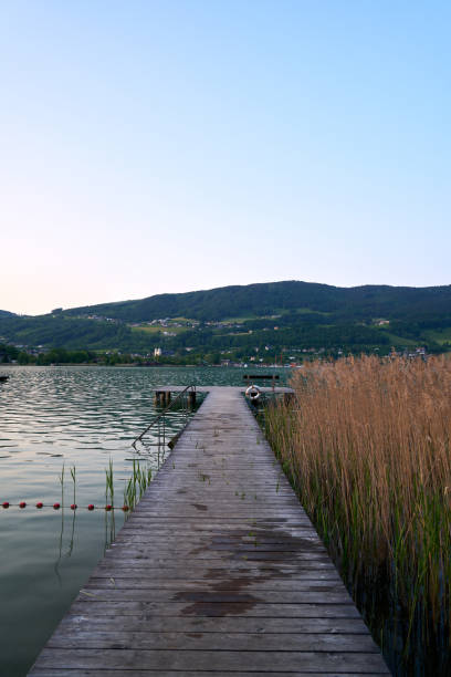 lake mondsee in alps mountains, austria. beautiful sunset landscape, with boats and pier. - seepromenade imagens e fotografias de stock