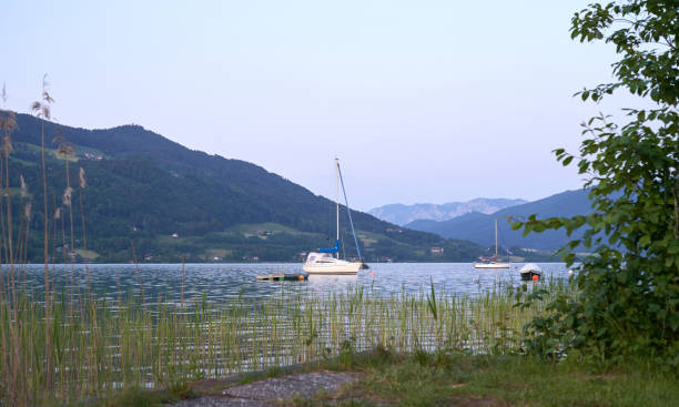 lake mondsee in alps mountains, austria. beautiful sunset landscape, with boats and pier. - seepromenade imagens e fotografias de stock