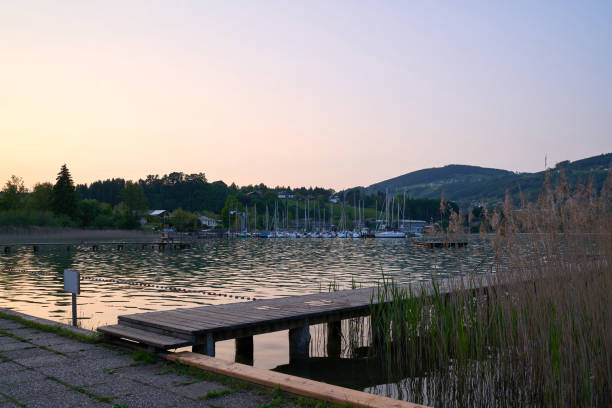 lake mondsee in alps mountains, austria. beautiful sunset landscape, with boats and pier. - seepromenade imagens e fotografias de stock