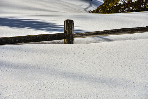 Heavy snow pack in rural North Dakota nearly covers wood split  rail fence .