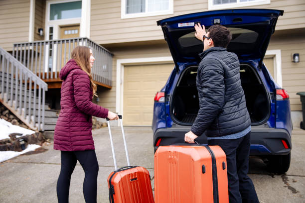 istock Young couple loading suitcases into car trunk, ready for an adventure 1956169283
