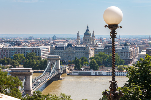 Budapest, Hungary. June, 19 - 2023: Chain Bridge crossing over the Danube river towards St Stephen basilica.\nBudapest, Hungary