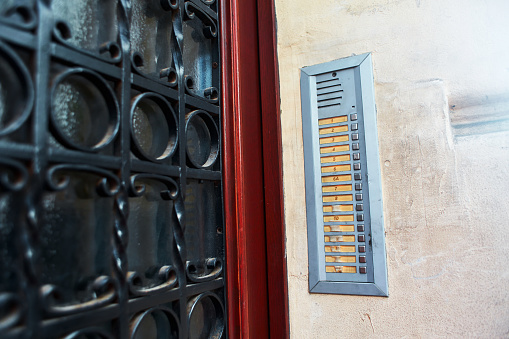 An old intercom with the names of the tenants is built into the wall at the front door of an old European house