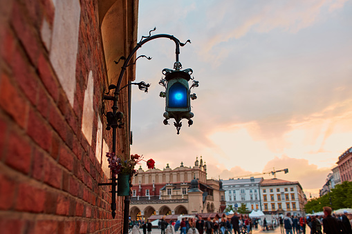 An old blue lantern made of handmade metal hangs on a brick wall in the historic streets of Krakow