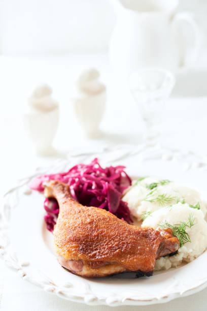 istock Roast duck with red cabbage and mashed potatoes on bright background. Close up. 1956635965