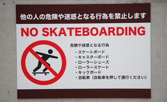 Illustration and text sign prohibiting skateboarding on the wall of a plaza in Japan