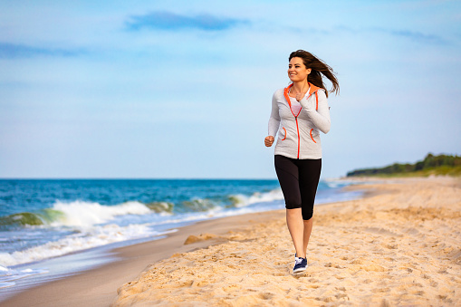 Beautiful woman running on sunny beach