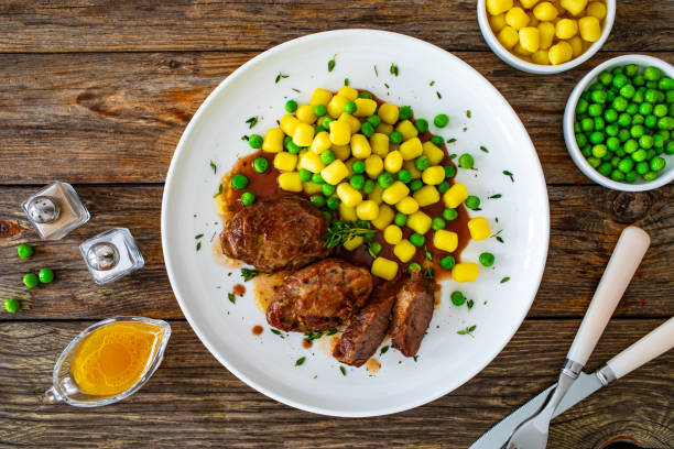 baked pork cheeks in sauce with gnocchi and green peas on wooden table - steak plate gourmet beef imagens e fotografias de stock