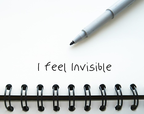Pen wrote on notebook I FEEL INVISIBLE - feeling ignored or overlooked by the people around - no one recognize your existence - Experiencing social rejection contribute to invisibility feeling
