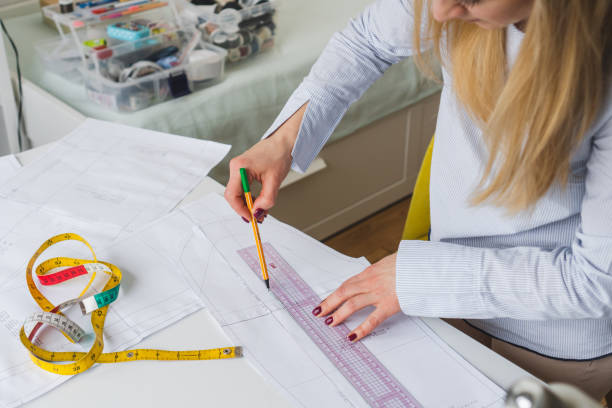 istock Female designer drawing paper patterns. Exclusive clothes making concept. Workplace of seamstress 1956755166