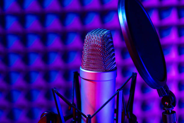 istock Professional studio microphone against acoustic foam panel background in neon light 1956775669