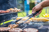 Chicken meat on grill being flipped with tongs
