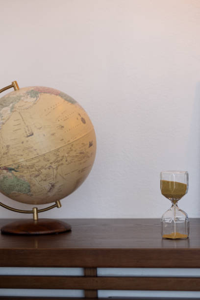 istock a globe with a copper axis and an hourglass on the table. A place to copy 1956787389