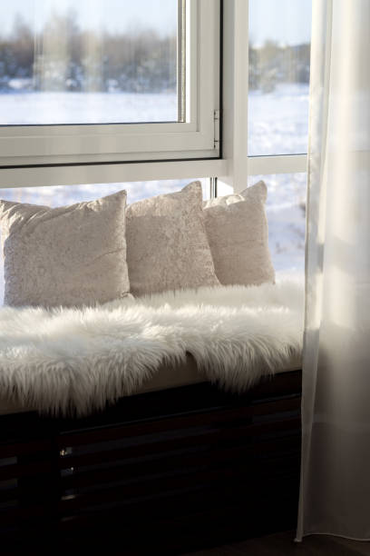 istock A cozy window sill sofa covered with white fur and pillows by the window overlooking the snowy landscape 1956791587